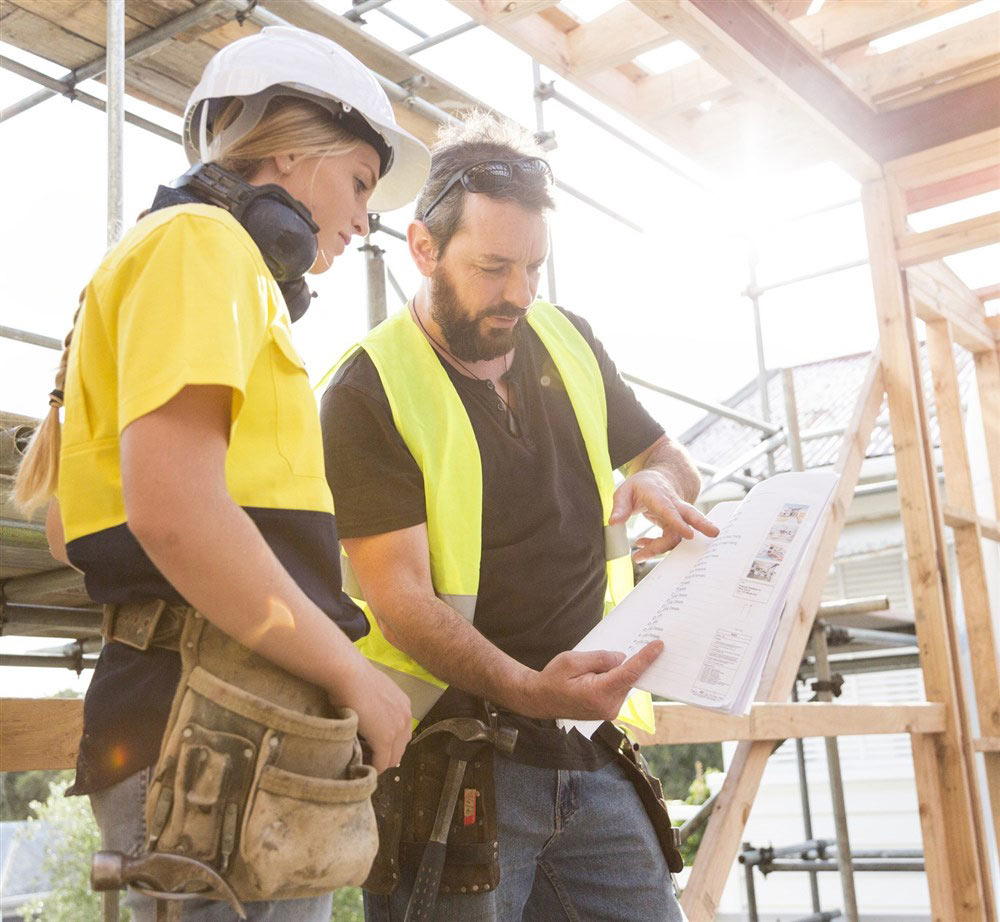 Två hantverkare kollar på en ritning